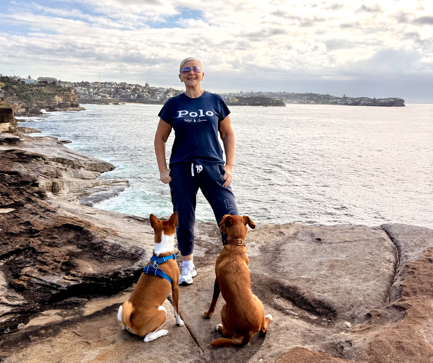 Jayne in blue with two attentive dogs at her feet on the coast